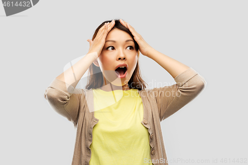 Image of stressed asian woman holding to her head