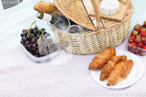 Image of picnic basket, food and wine glasses on blanket