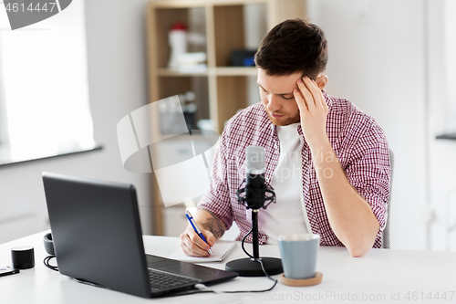 Image of audio blogger with laptop, microphone and notebook