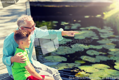 Image of grandfather and grandson sitting on river berth