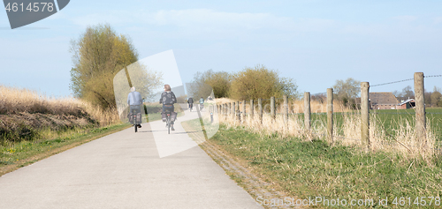 Image of Rear view of people riding bikes on bicycle path
