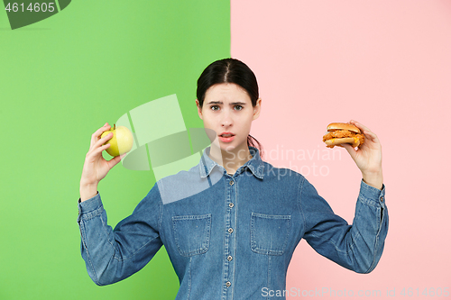 Image of Diet. Dieting concept. Healthy Food. Beautiful Young Woman choosing between fruits and unhelathy fast food