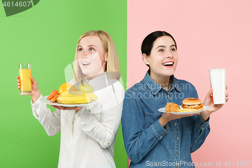 Image of Diet. Dieting concept. Healthy Food. Beautiful Young Women choosing between fruits and unhelathy fast food