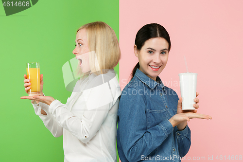 Image of Diet. Dieting concept. Healthy Food. Beautiful Young Women choosing between fruit orange juice and unhelathy carbonated sweet drink