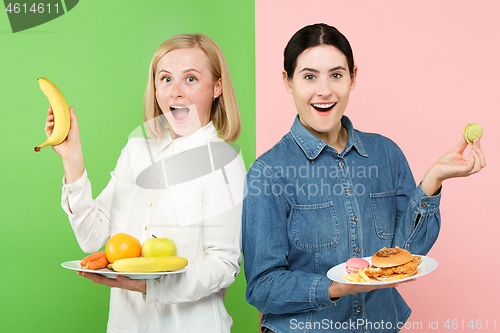 Image of Diet. Dieting concept. Healthy Food. Beautiful Young Women choosing between fruits and unhelathy fast food