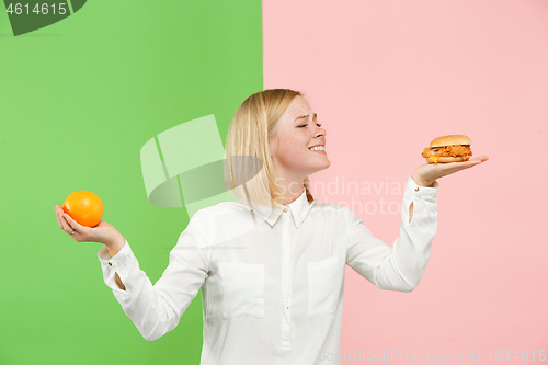 Image of Diet. Dieting concept. Healthy Food. Beautiful Young Woman choosing between fruits and unhelathy fast food