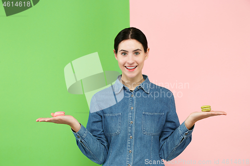 Image of Young beautiful woman holding macaroons pastry in her hands