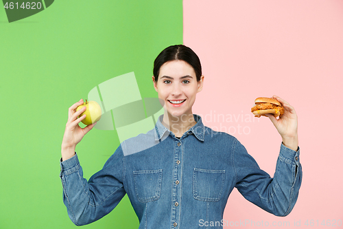 Image of Diet. Dieting concept. Healthy Food. Beautiful Young Woman choosing between fruits and unhelathy fast food