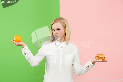 Image of Diet. Dieting concept. Healthy Food. Beautiful Young Woman choosing between fruits and unhelathy fast food