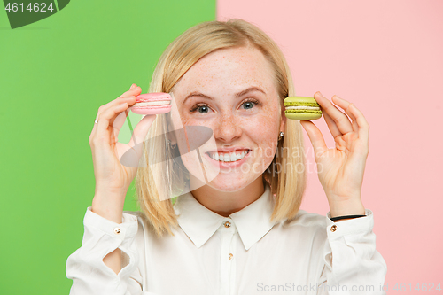 Image of Young beautiful woman holding macaroons pastry in her hands