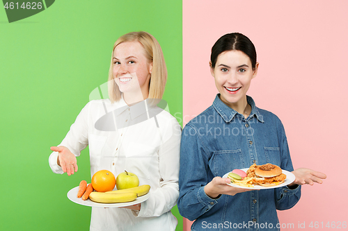 Image of Diet. Dieting concept. Healthy Food. Beautiful Young Women choosing between fruits and unhelathy fast food