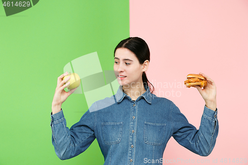 Image of Diet. Dieting concept. Healthy Food. Beautiful Young Woman choosing between fruits and unhelathy fast food