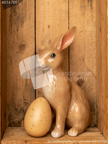 Image of sweet easter bunny figure with an egg in a wooden box