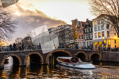 Image of Beautiful tranquil scene of city of Amsterdam at dusk. Bicycles along the street and on the bridge over the canal.