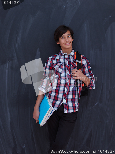 Image of arab teenager  with school backpack and books against black chal