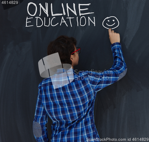 Image of Teen Boy with chalk  writing on black chalkboard online educatio