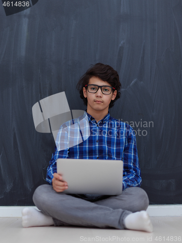 Image of Arab teenager using laptop to work on homework  at home