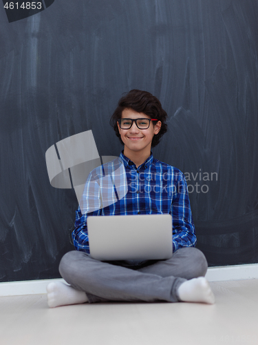 Image of Arab teenager using laptop to work on homework  at home
