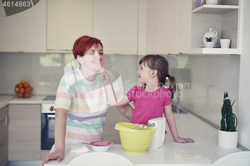 Image of Mother and daughter playing and preparing dough in the kitchen.