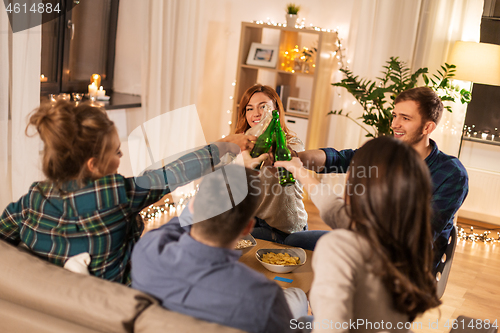 Image of friends clinking drinks at home in evening