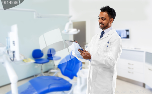 Image of indian dentist with clipboard at dental clinic