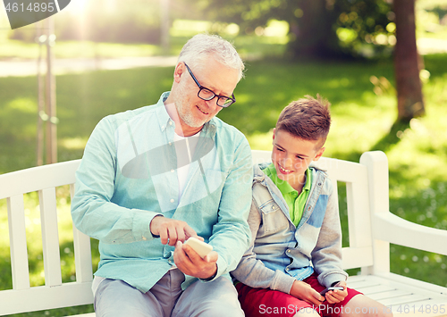 Image of old man and boy with smartphones at summer park