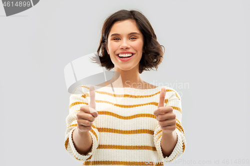 Image of smiling woman in pullover showing thumbs up