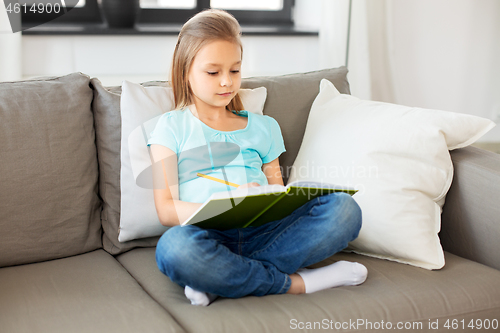 Image of little girl with diary sitting on sofa at home