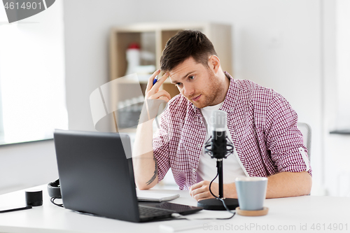 Image of audio blogger with laptop, microphone and notebook