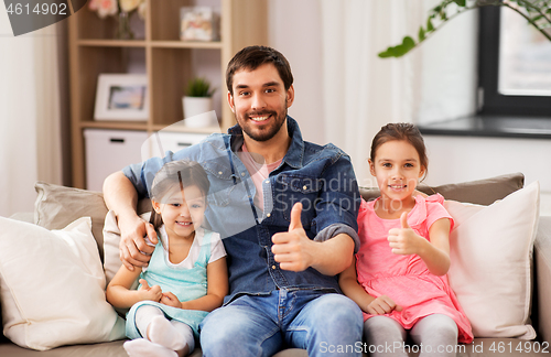 Image of father with daughters showing thumbs up at home