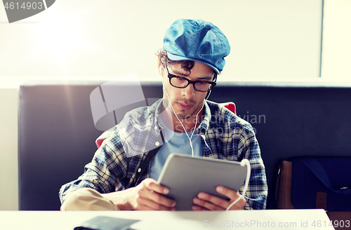 Image of man with tablet pc and earphones sitting at cafe