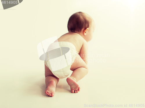 Image of little baby in diaper crawling on white floor