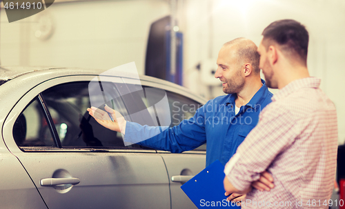 Image of auto mechanic with clipboard and man at car shop