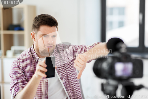 Image of male blogger with smartphone videoblogging at home