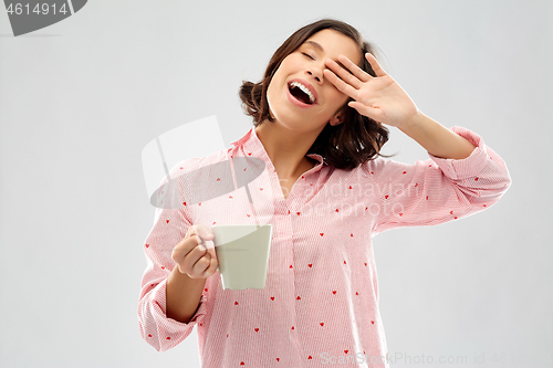 Image of happy yawning young woman in pajama with coffee