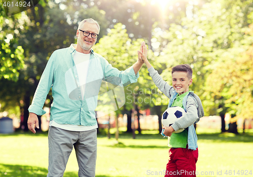 Image of old man and boy with soccer ball making high five