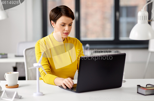 Image of happy businesswoman with laptop working at office