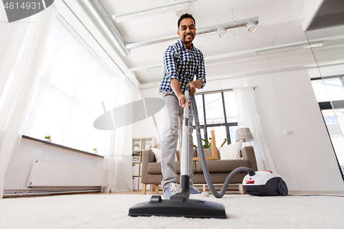 Image of indian man with vacuum cleaner at home