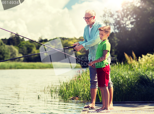 Image of grandfather and grandson fishing on river berth