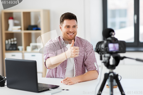 Image of male blogger with camera videoblogging at home