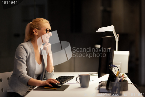 Image of businesswoman at computer working at night office