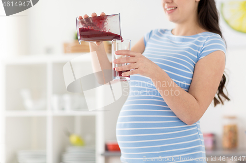 Image of pregnant woman pouring fruit smoothie at home