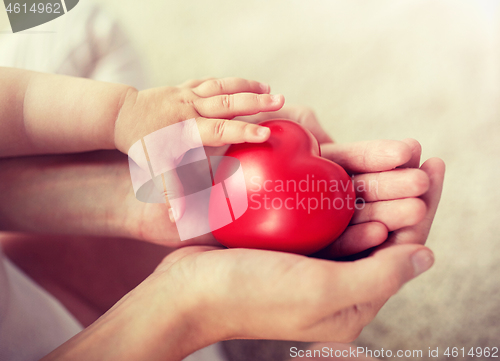 Image of close up of baby and mother hands with red heart