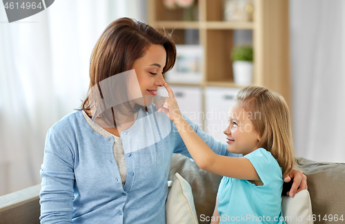 Image of mother and daughter sitting on sofa at home