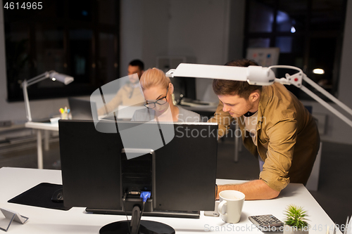 Image of business team with computer working late at office