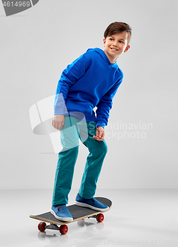 Image of smiling boy in blue hoodie with skateboard