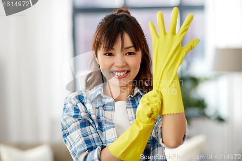 Image of asian woman in rubber gloves cleaning at home