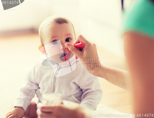 Image of mother with spoon feeding little baby at home