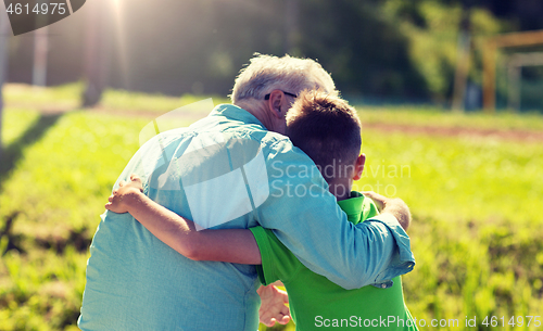 Image of grandfather and grandson hugging outdoors