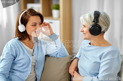 Image of senior mother and adult daughter with headphones